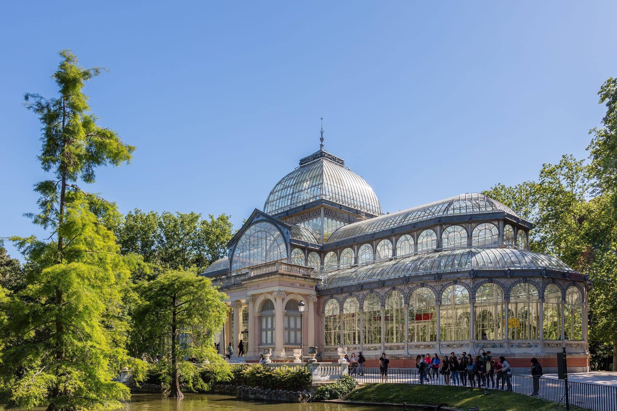 The glass-and-iron Palacio de Cristal in Retiro Park, framed by trees beside its pond