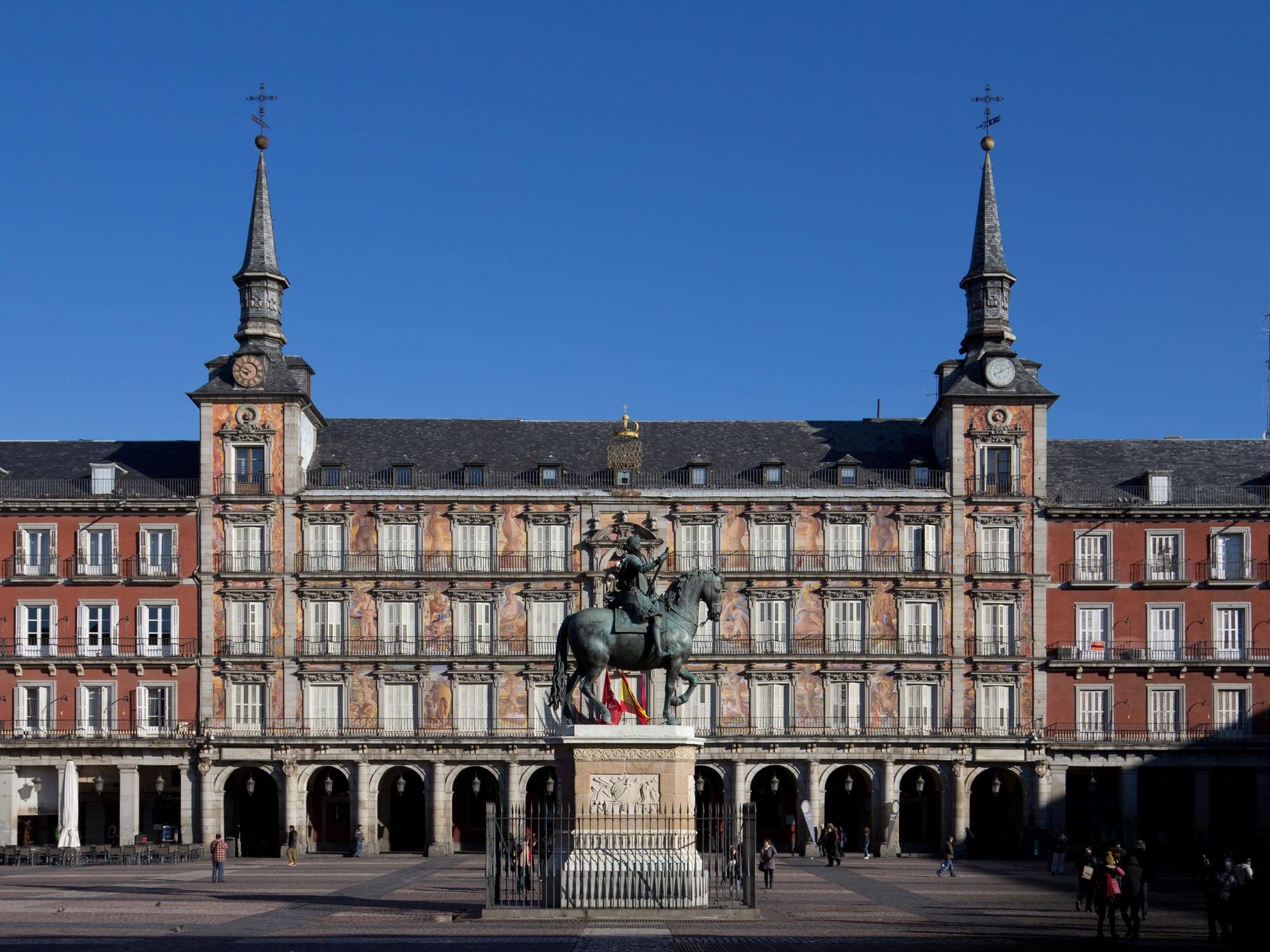 Plaza Mayor in Madrid: the Casa de la Panadería with its twin spires and the equestrian statue of Philip III under a clear sky